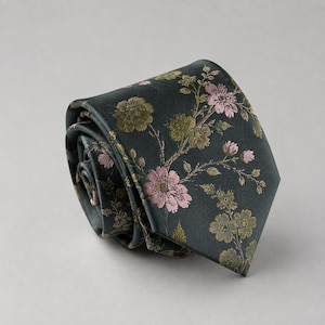 May include: A dark green necktie featuring a floral pattern with light pink and muted gold blossoms and leaves. The tie is rolled into a coil, displaying the smooth fabric texture and the intricate botanical print across the visible surface area.