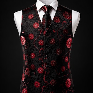 Puede incluir: Un chaleco negro con un patrón floral rojo vibrante y una corbata a juego sobre una camisa blanca de cuello rígido. El chaleco tiene cierre frontal de botones, dos bolsillos delanteros y una textura de tela jacquard detallada en toda la prenda.