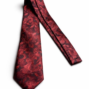 Könnte beinhalten: Eine rote Krawatte mit floralem Muster. Die Krawatte hat einen tiefroten Farbton mit einem dunkleren roten Blumendesign. Sie besteht aus einem glatten Material und wird auf weißem Hintergrund präsentiert.