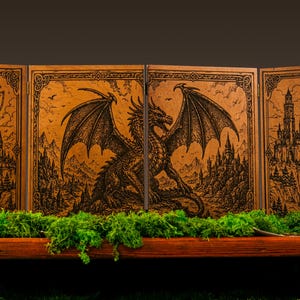 May include: A four-panel wooden screen featuring intricate laser-engraved illustrations of a large dragon with spread wings, towering castles on cliffs, and mountain landscapes, all framed by decorative borders on a light brown wood surface.