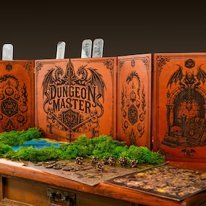 May include: A multi-panel orange leather Dungeon Master screen featuring black laser-engraved illustrations of dragons, dice, and a gargoyle. The screen displays the text Dungeon Master and includes green moss accents and game pieces.