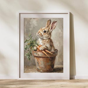 May include: Framed art print of a brown and white rabbit in a terracotta pot, holding carrots with green tops. The painting has a soft, painterly style with a neutral background, suitable for a nursery.