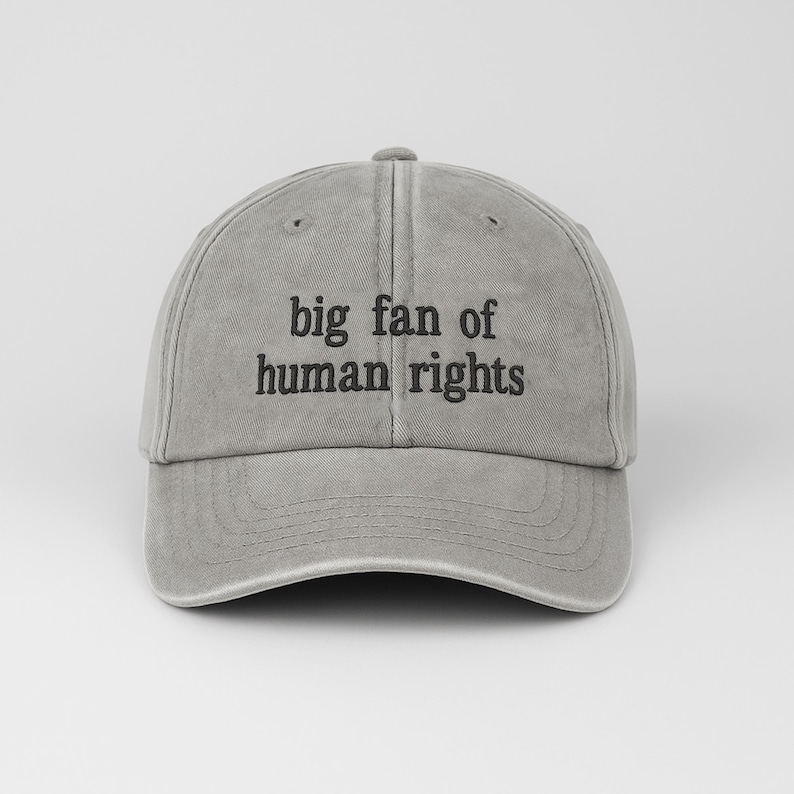 May include: A gray baseball cap with the text "big fan of human rights" in black. The cap has a curved brim and an adjustable strap at the back. The hat is made of a soft, worn material.