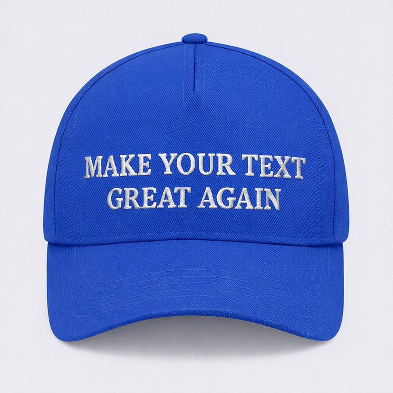 May include: A royal blue baseball cap with a curved brim. The cap features white embroidered text that reads "MAKE YOUR TEXT GREAT AGAIN". The cap has a button on top and an adjustable strap.