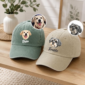 May include: A sage green baseball cap featuring a printed portrait of a golden dog and the name Rosie, alongside a beige baseball cap with a printed portrait of a black and grey dog and the name Freddie, both with matching circular photo insets.