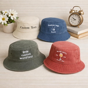 May include: Four bucket hats in cream, blue, green, and red. Each hat has custom text or a logo. The cream hat says "Custom Text", the blue hat has a dog logo, the green hat says "little custom word/text", and the red hat says "Margarita".