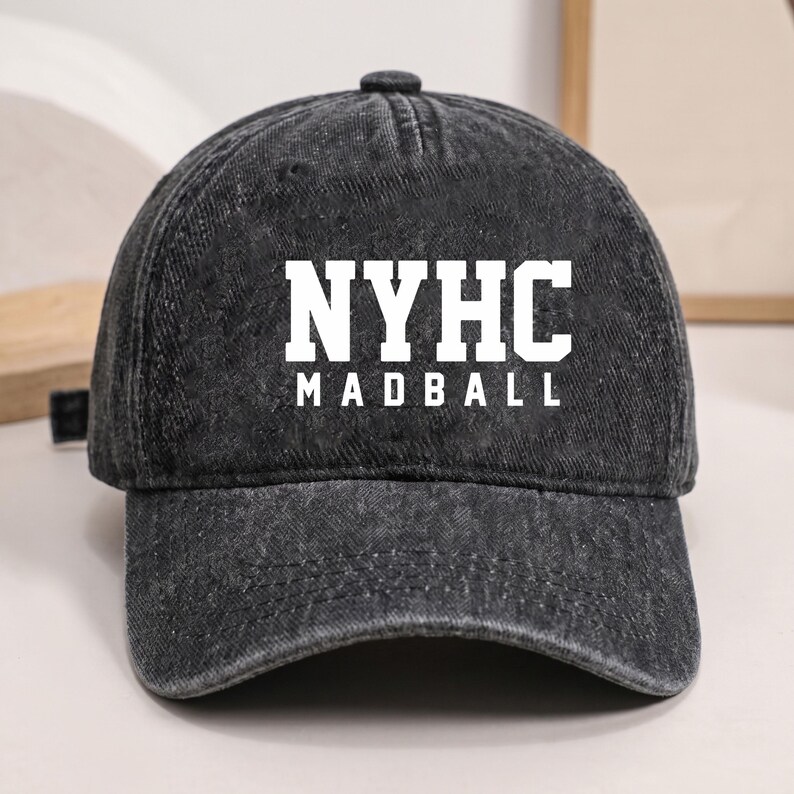 Puede incluir: Una gorra de b&eacute;isbol negra con efecto de lavado &aacute;cido que presenta el texto blanco NYHC en la l&iacute;nea superior y MADBALL en la l&iacute;nea inferior. La gorra tiene una corona estructurada, una visera curva y un bot&oacute;n en la parte superior central.