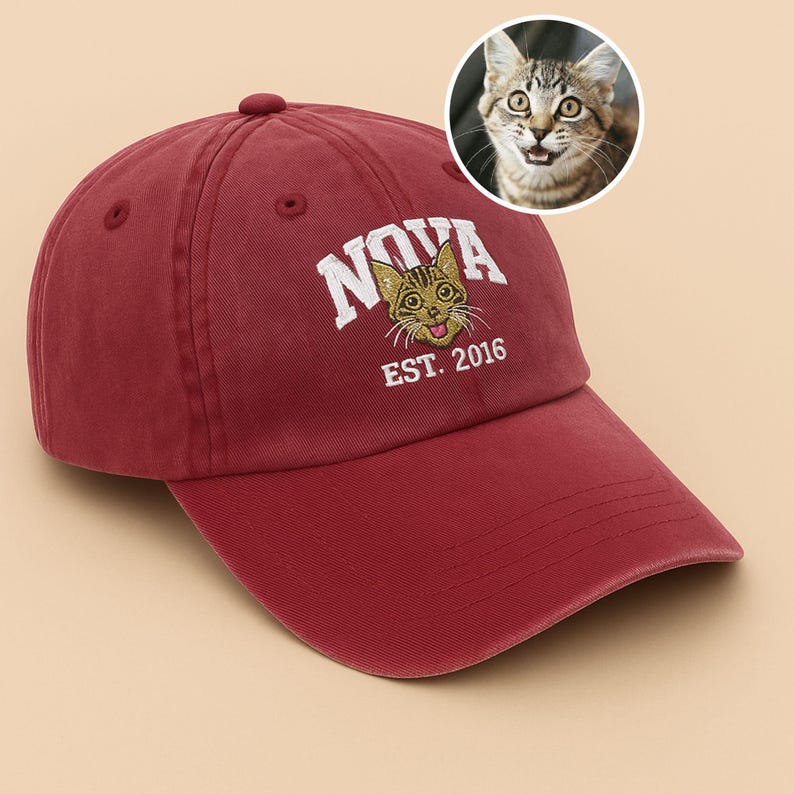 May include: A maroon baseball cap featuring the word "NOVA" in white, with a cartoon cat graphic. The text "EST. 2016" is below the cat graphic. A small image of a cat is in the upper right corner.