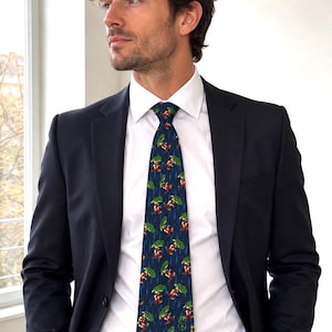 May include: A dark blue necktie featuring a repeating pattern of small figures holding green umbrellas during a rainstorm, worn with a crisp white collared shirt and a tailored black suit jacket with a black belt at the waist.