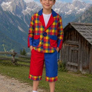 May include: A blazer and shorts set featuring a multi-colored plaid pattern in red, yellow, and blue. The blazer has a solid blue collar, red lapels, and blue pocket flaps with a single blue button. The shorts are color-blocked in red and blue.