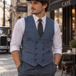 May include: A double-breasted blue plaid waistcoat worn over a crisp white long-sleeve button-down shirt with a dark brown necktie, paired with dark grey trousers and a charcoal grey tweed flat cap, creating a classic and structured layered ensemble.