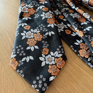 Elegante cravatta di lusso in seta fatta a mano con fiori neri, arancioni e bianchi.