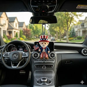 May include: A crocheted Uncle Sam car charm hanging from a car's rearview mirror. The charm features a red, white, and blue top hat, a blue jacket, and red and white striped pants. An American flag is held in one hand.