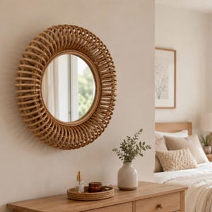 May include: A round wall mirror featuring a frame constructed from coiled light brown rattan. The circular glass surface is surrounded by multiple layers of spiraling natural cane, creating a textured, layered appearance with a warm, neutral tone.