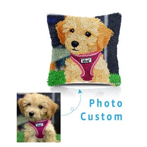 May include: A square, textured pillow featuring a golden retriever puppy wearing a pink harness. The puppy's image is in the center, surrounded by a dark blue and green background. The words "Photo Custom" are below the pillow.