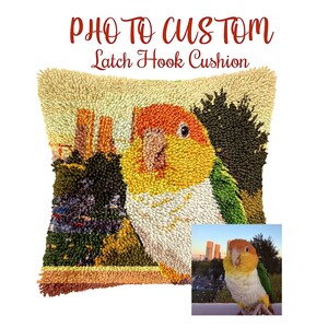 May include: A square latch hook cushion featuring a colorful parrot design. The parrot has orange, yellow, green, and white feathers. The cushion has a beige background with the words "PHOTO TO CUSTOM Latch Hook Cushion" in red and black.