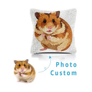 May include: A square, white, textured pillow featuring a detailed, embroidered hamster design in shades of brown and tan. The image includes a real hamster and the text "Photo Custom".