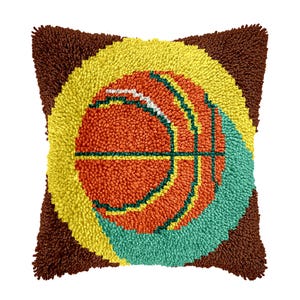 May include: Square decorative pillow featuring a basketball design. The pillow has a brown border, a yellow circle, and a basketball in shades of orange, green, and white. The design is made with a textured, looped fabric.
