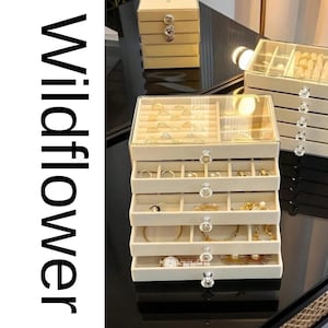 Caja organizadora de joyas de terciopelo con tapa de cristal y múltiples cajones.