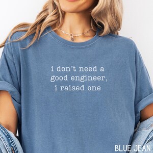 May include: Blue jean coloured t-shirt with the text "i don't need a good engineer, i raised one" in white. The shirt has a crew neck and short sleeves. The words "BLUE JEAN" are at the bottom right.