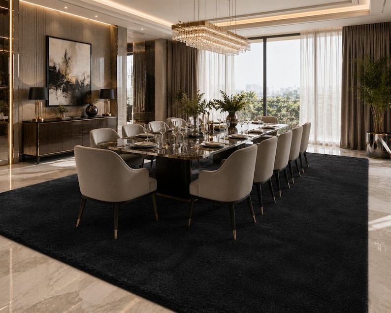 May include: A formal dining room featuring a long rectangular table with a dark marble top, surrounded by ten upholstered beige chairs with dark legs. A large crystal chandelier hangs above, and a black area rug covers the floor.
