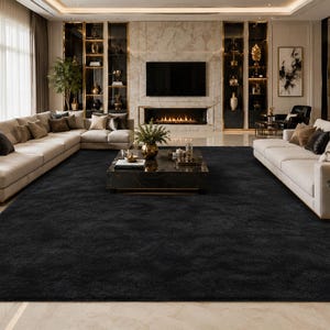 May include: A large, rectangular area rug featuring a solid, deep black color with a soft, plush, and textured pile surface. The rug is positioned centrally in a living room, covering a significant portion of the light-colored marble floor.
