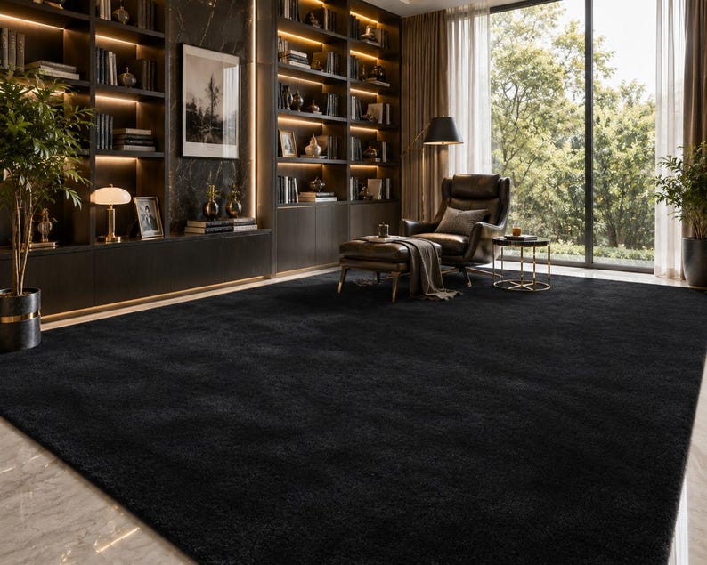May include: A large, solid black area rug with a dense, soft-textured pile. The rectangular rug features a uniform dark color and covers a significant portion of the floor, providing a deep, matte surface that contrasts with the light marble flooring.
