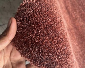 May include: A thick, rust-colored rug with a dense, tufted pile texture. The material features a deep, earthy terracotta hue with a consistent, looped construction that creates a soft, plush surface across the entire visible area of the textile.