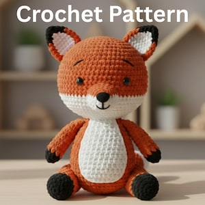 May include: A crocheted fox toy in orange, white, and black. The fox has a white chest and belly, black paws, and a black nose. The text "Crochet Pattern" is displayed at the top of the image.