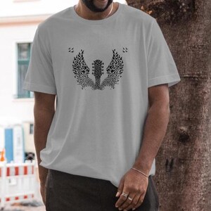 Op de afbeelding: Een lichtgrijs t-shirt met een zwarte afbeelding van een gitaar met vleugels gemaakt van kleine vogels. Het ontwerp is gecentreerd op het shirt. Het shirt heeft korte mouwen en een ronde hals.