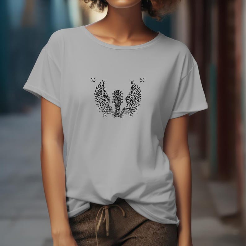 Op de afbeelding: Lichtgrijs t-shirt met een zwart grafisch ontwerp van een gitaar met vleugels gemaakt van vogels. Het ontwerp is gecentreerd op de voorkant. Het shirt heeft korte mouwen en een ronde hals.
