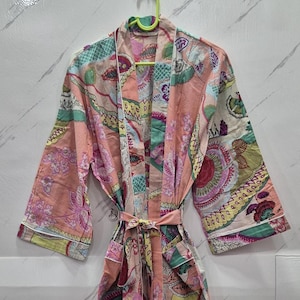 May include: A long-sleeved robe featuring a light peach base color with a multi-colored floral and paisley pattern in shades of green, yellow, pink, and purple. The garment includes a matching fabric tie belt and white piping along the edges.