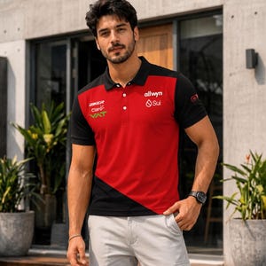 May include: A short-sleeved polo shirt featuring a color-blocked design in red and black. The shirt includes a collar with three buttons and various printed logos, including BIKER, Claro, VAT, allwyn, and Sui, displayed on the chest area.