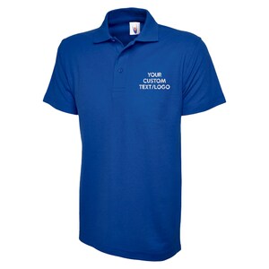 May include: A royal blue polo shirt with a collar and short sleeves. The shirt has a three-button placket and the text "YOUR CUSTOM TEXT/LOGO" printed in white on the chest. The shirt is made of a smooth, likely synthetic fabric.