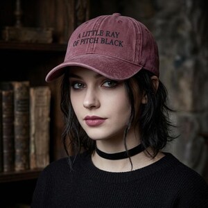 Può includere: Cappellino da baseball bordeaux con la scritta "A Little Ray of Pitch Black" in lettere nere. Il cappellino ha una visiera curva e un classico design a sei pannelli. Realizzato in un materiale morbido e usurato.