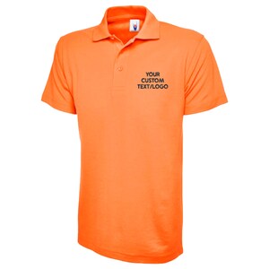 May include: Vibrant orange polo shirt with a collared neckline and short sleeves. The shirt has a three-button placket and the text "YOUR CUSTOM TEXT/LOGO" printed on the chest. The fabric appears to be a smooth, possibly synthetic material.