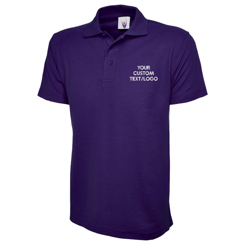 May include: A dark purple polo shirt with a collared neckline and short sleeves. The shirt has a three-button placket and the text "YOUR CUSTOM TEXT/LOGO" printed in white on the chest. The shirt is made of a smooth fabric.