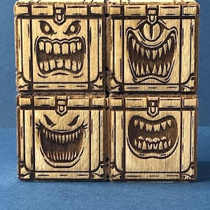 May include: Four square wooden boxes arranged in a grid, each featuring a laser-engraved design of a different monster face with sharp teeth and expressive eyes. The light-colored wood grain is visible, and the engravings are dark brown.
