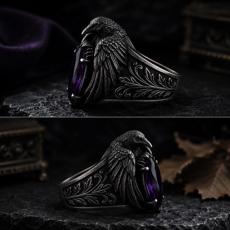 May include: A silver ring with a raven design, holding a large, oval-cut purple gemstone. The ring has detailed carvings on the band and a dark, antique finish. The raven's wings are spread, and the gemstone is a deep violet colour. The ring is a statement piece.