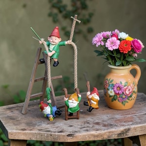 May include: A whimsical garden scene featuring miniature gnomes. One gnome climbs a wooden ladder, while others swing on rope swings. A vase with colorful flowers sits on a rustic wooden surface, adding a touch of nature to the playful arrangement.