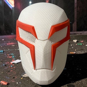 Puede incluir: Máscara blanca con detalles rojos, con un patrón geométrico y aberturas para los ojos. La máscara tiene un diseño futurista, con una superficie texturizada y formas angulares. Los acentos rojos enmarcan los ojos y añaden color.