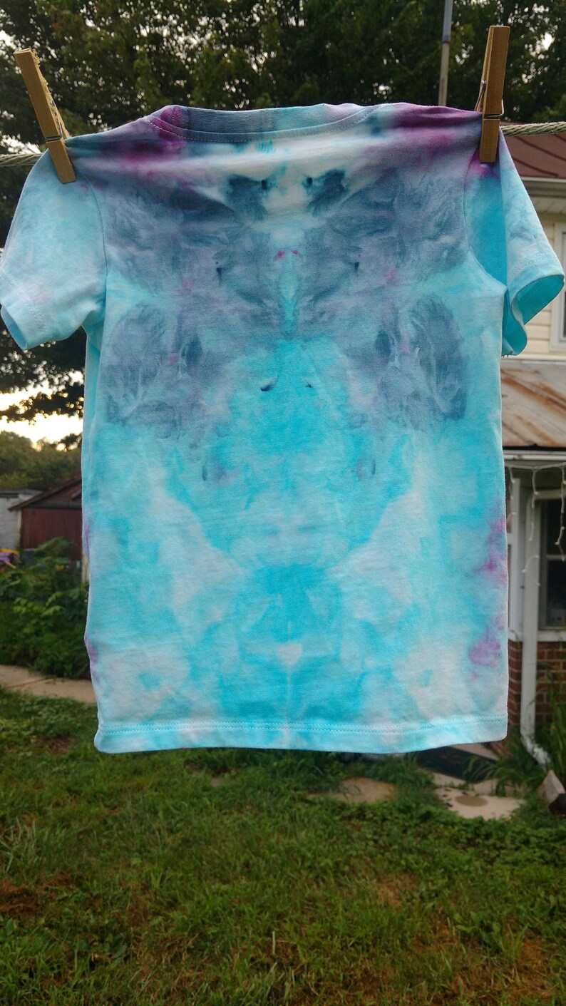 May include: A light blue tie-dye t-shirt with a white background and purple and blue accents.