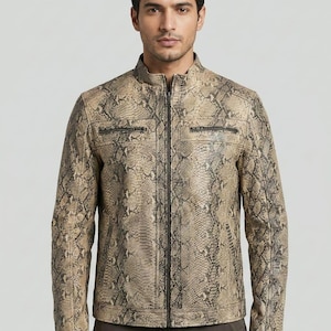 Może przedstawiać: Brązowo-czarna skórzana kurtka z wzorem skóry węża, ze stójką i zapięciem na zamek z przodu. Kurtka posiada dwie kieszenie na piersi zapinane na zamek i długie rękawy. Kurtka jest w neutralnym kolorze i pasuje do wielu stylizacji. Długość kurtki to około 60 cm.