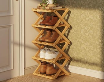May include: A natural wood, folding shoe rack with five shelves. The rack holds various pairs of shoes, including brown leather boots and white sneakers. The rack is positioned against a wall with a floral pattern.