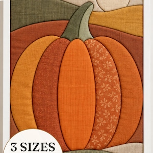 May include: A framed fabric wall art piece featuring a stylised pumpkin in shades of orange, brown, and green with a textured finish. The text INSTANT DOWNLOAD appears at the top, and a circular graphic indicates 3 SIZES: 5x7", 6x6", and 8x10".