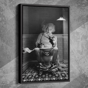 以下が含まれることがあります： 黒と白の額入りプリント。アインシュタインがトイレに座り、紙に書き物をしている。彼はパイプを持っています。背景には、模様のあるタイルの床と照明器具のあるバスルームが写っています。
