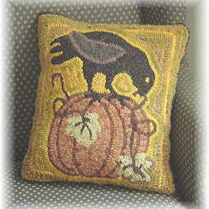 May include: A hand-stitched pillow with a black crow perched on top of a brown and yellow pumpkin. The pillow has a yellow border and is made with a variety of textures.