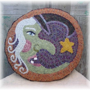 Peut inclure: Un tapis rond en crochet &agrave; la main avec un motif fantaisiste d'un visage de sorci&egrave;re avec un long nez et une &eacute;toile. Le tapis est fait de plusieurs couleurs, dont le vert, le violet, l'orange et le jaune.