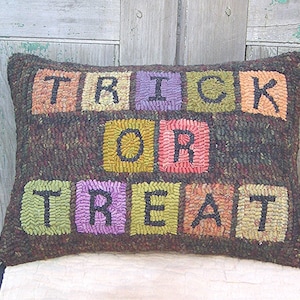 Peut inclure: Un coussin brun avec les mots "Trick or Treat" &eacute;crits en carr&eacute;s color&eacute;s. Chaque lettre est dans un carr&eacute; de couleur diff&eacute;rente, avec les "T" en vert, les "R" en violet, le "I" en orange, le "C" en jaune, le "O" en rose et le "E" en marron.