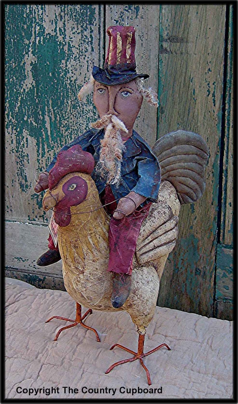 May include: A handmade folk art doll dressed as Uncle Sam riding a rooster. The doll is wearing a red, white, and blue hat, a blue jacket, and red pants. The rooster is painted in shades of brown and yellow.